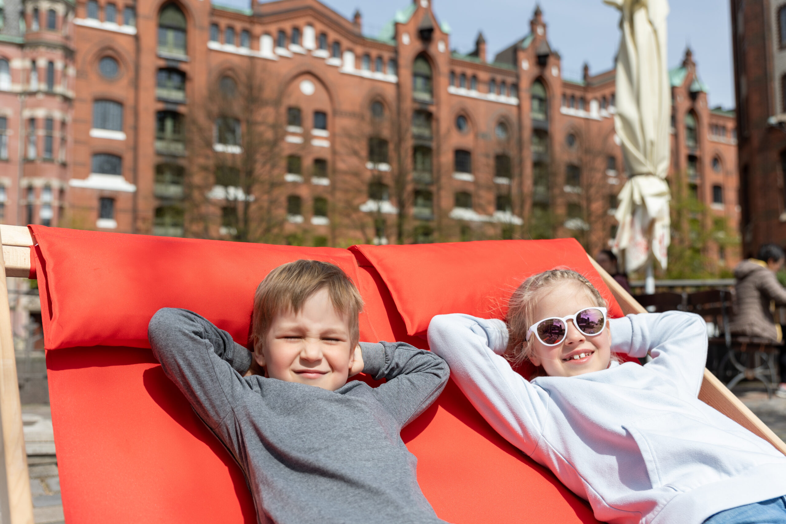 Zwei Kinder genießen die Sonne in der Speicherstadt.