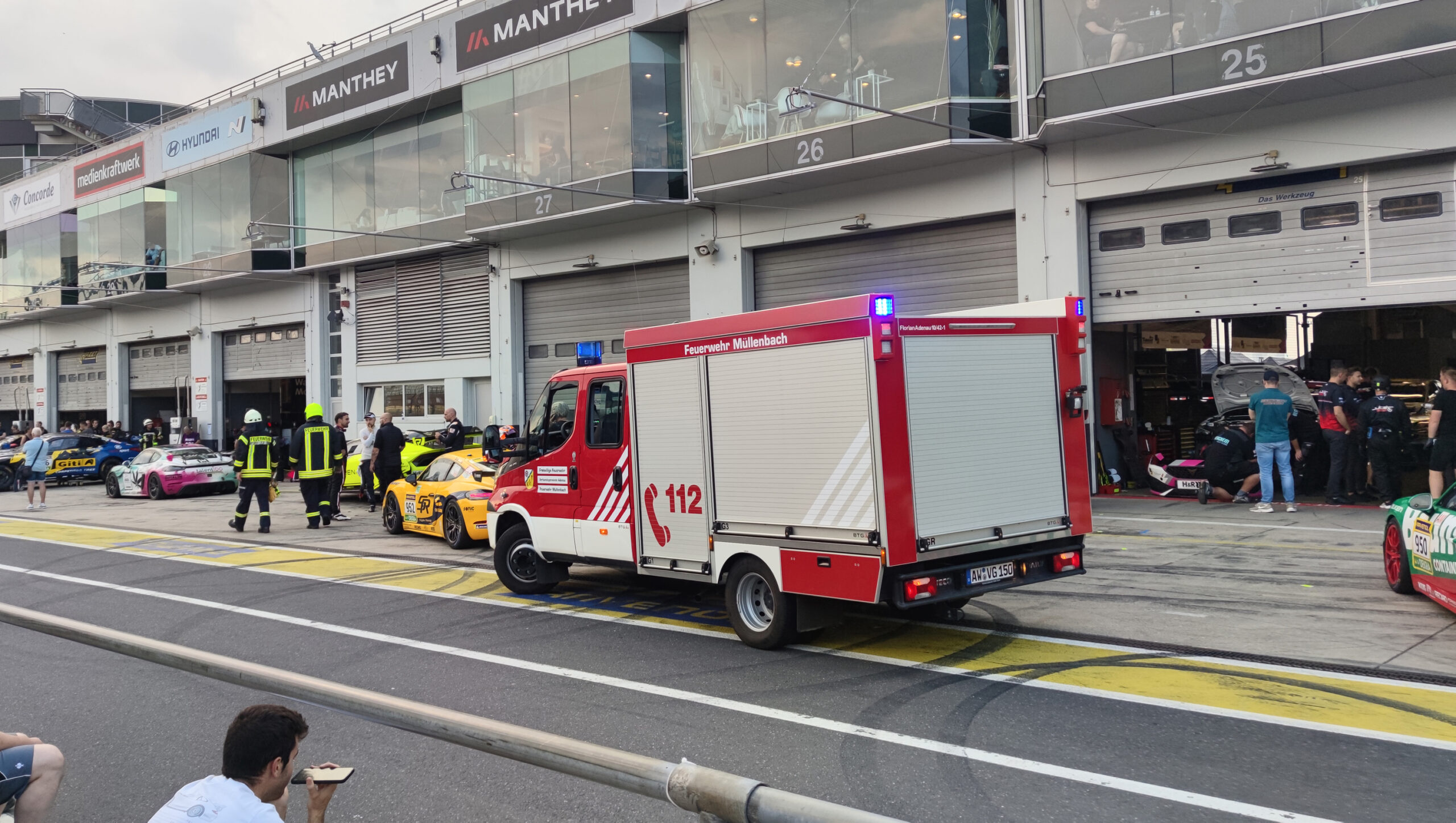 Feuerwehrleute laufen vor Box 27 in der Boxengasse des Nürburgrings.