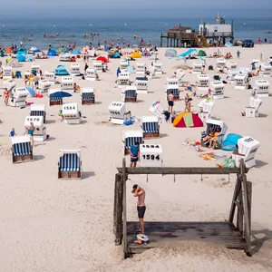 Sankt Peter-Ording: Zahlreiche Touristen sind bei Sonnenschein am Strand an der Nordsee unterwegs.