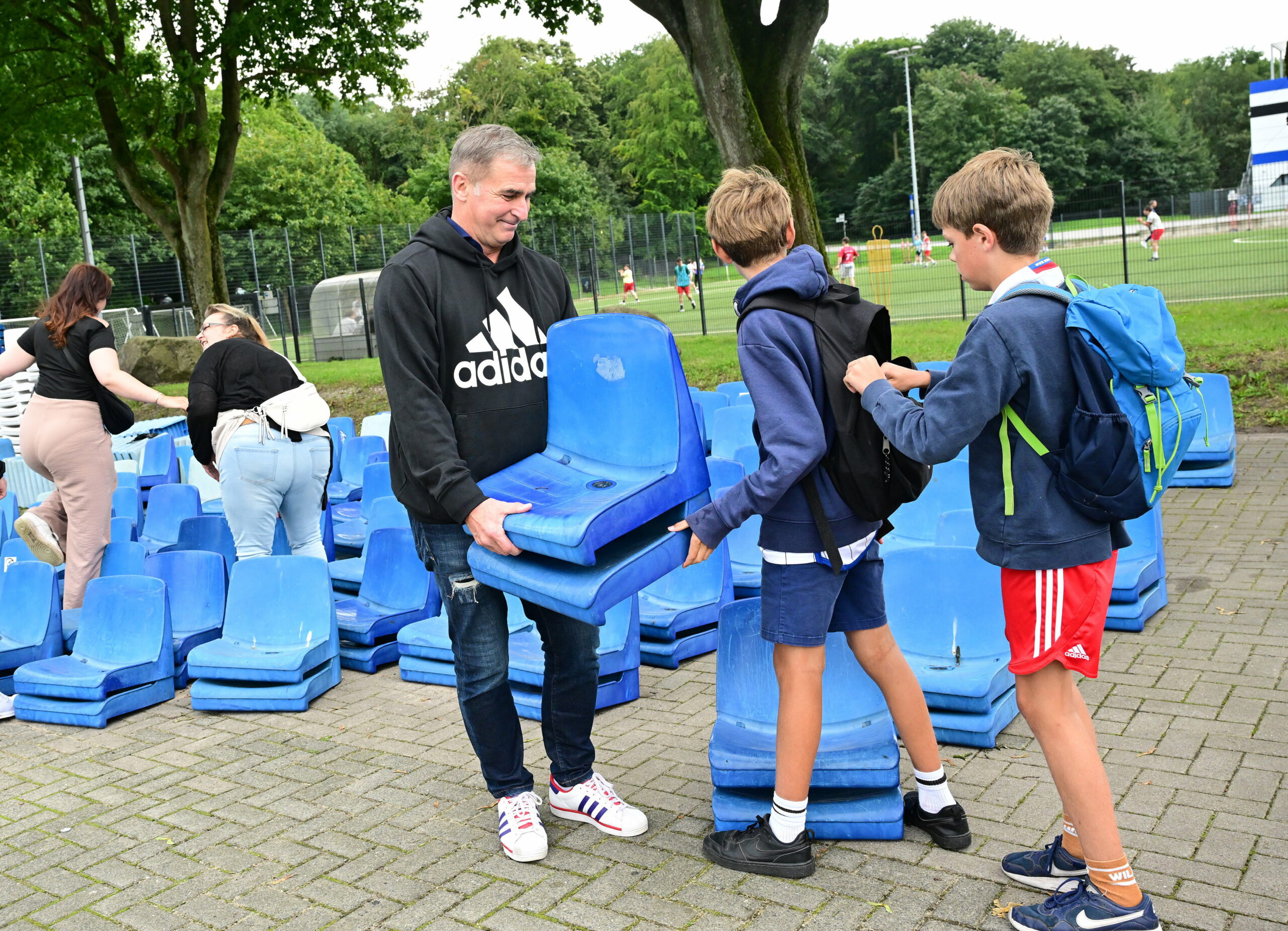 HSV-Vorstand Stefan Kuntz macht zwei junge Fans mit Sitzschalen glücklich.