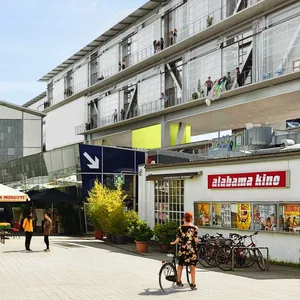 So soll die Kampnagel-Piazza einmal aussehen: Die neue Halle (r.) soll auf Stelzen über das bestehende Gebäude mit Kino, Restaurant und Haupteingang gebaut werden.