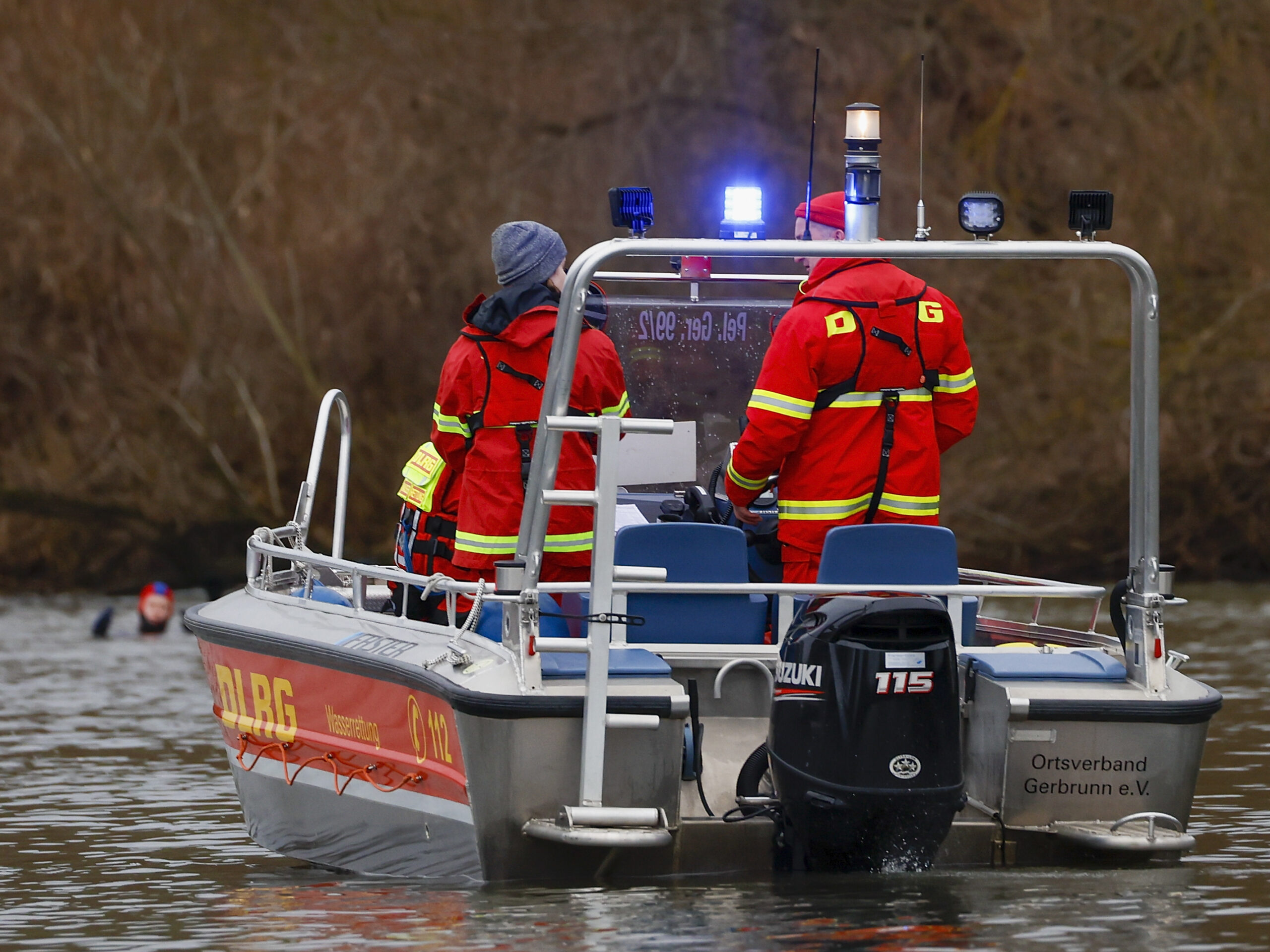 Zwei Rettungskräfte des DLRG stehen auf einem Rettungsboot.