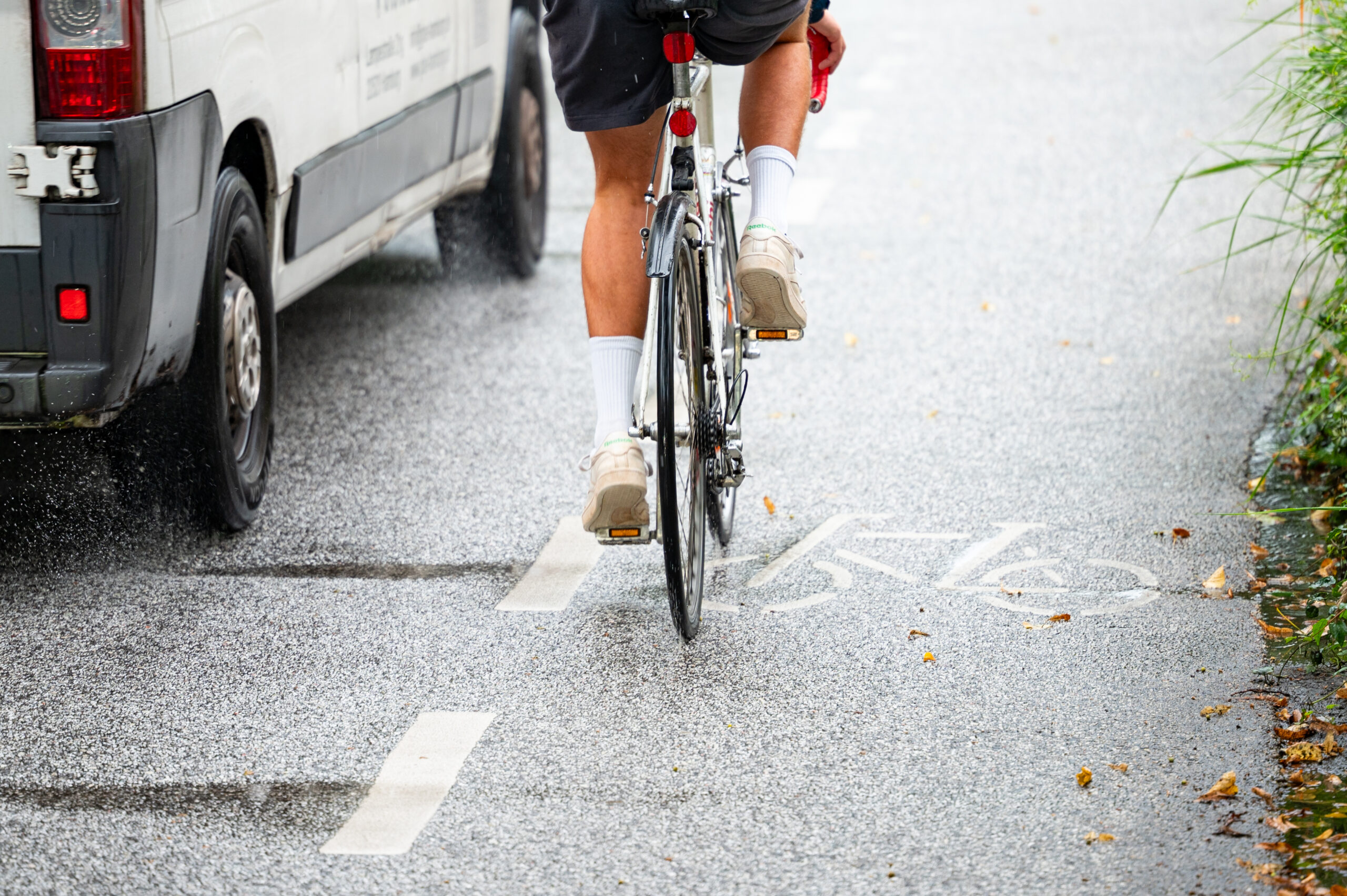 Ein Fahrradfahrer auf dem Fahrradschutzstreifen wird von einem Transporter sehr nah überholt.