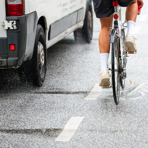 Ein Fahrradfahrer auf dem Fahrradschutzstreifen wird von einem Transporter sehr nah überholt.