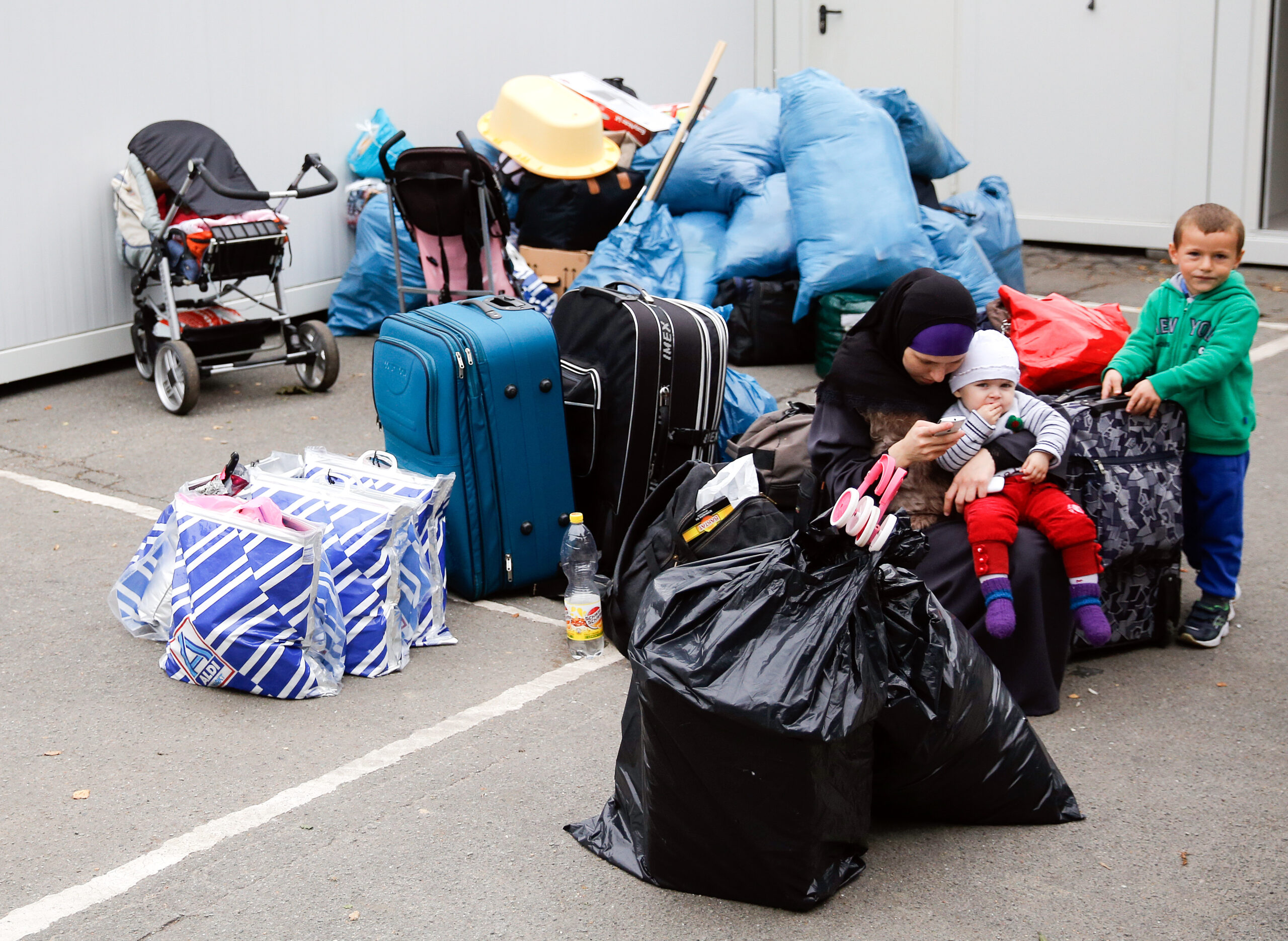 Eine Flüchtlingsfamilie sitzt in Hamburg zwischen ihrem Gepäck vor einem Wohncontainer.