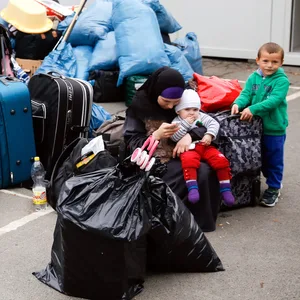 Eine Flüchtlingsfamilie sitzt in Hamburg zwischen ihrem Gepäck vor einem Wohncontainer.
