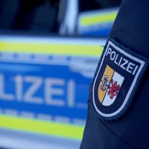 Eine Polizistin steht neben einem Einsatzfahrzeug.