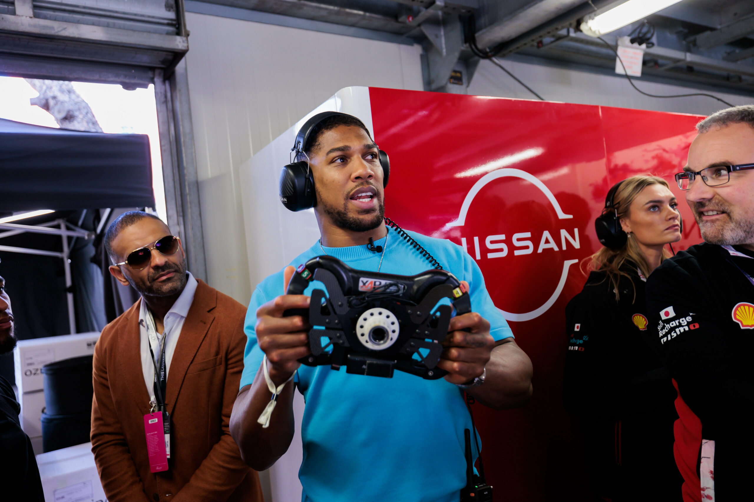 Anthony Joshua hält ein Lenkrad von einem Formel E-Auto in der Hand.