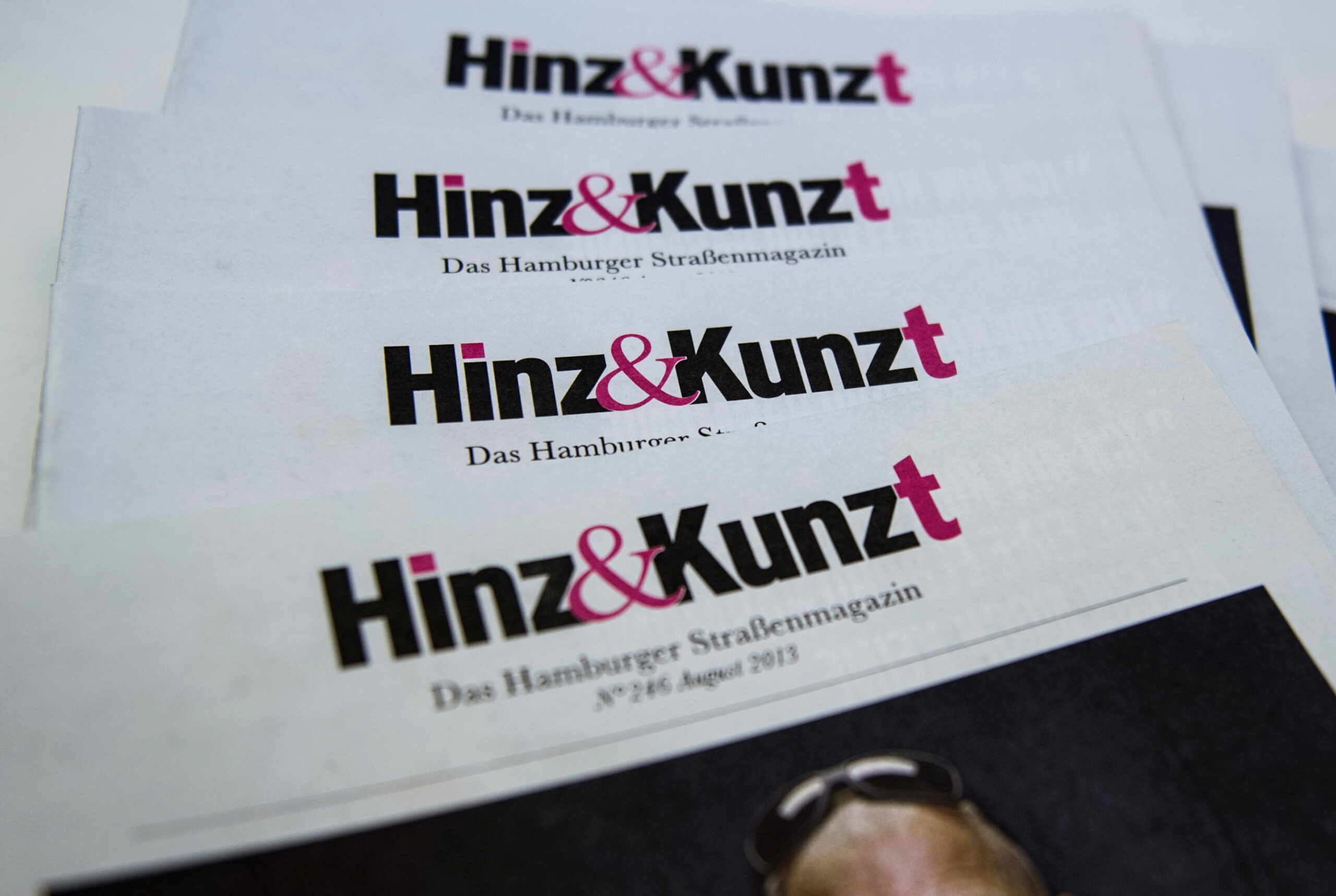 Mehrere Ausgaben des Straßenmagazins „Hinz & Kunzt“ liegen auf einem Tisch.