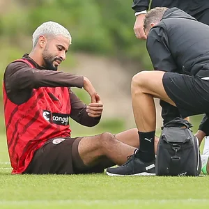 Elias Saad wird von St. Pauli-Physios behandelt und sitzt auf dem Boden.
