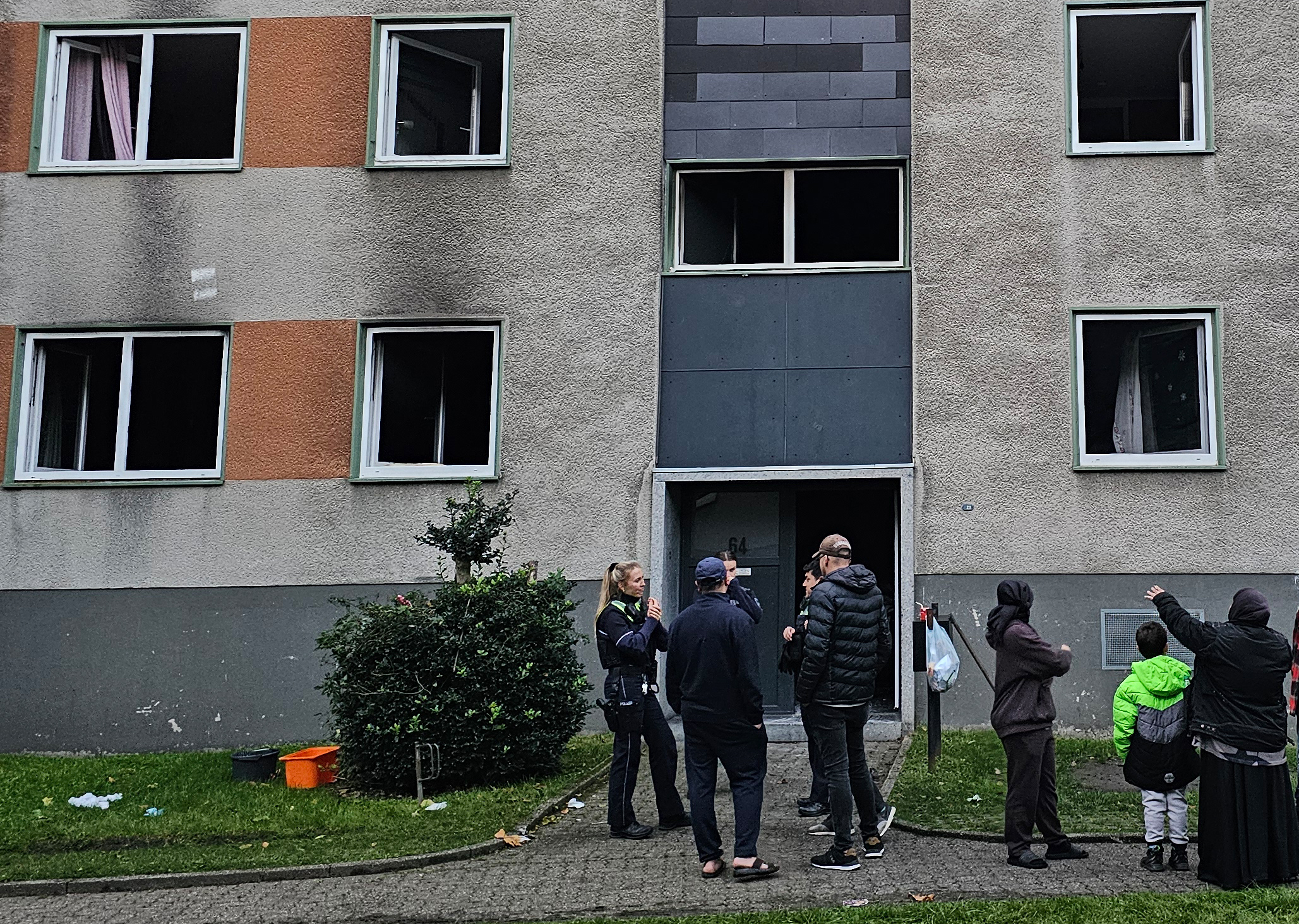 Polizisten stehen nach einem Brend in Essen mit Bewohnern vor einem Wohnhaus.