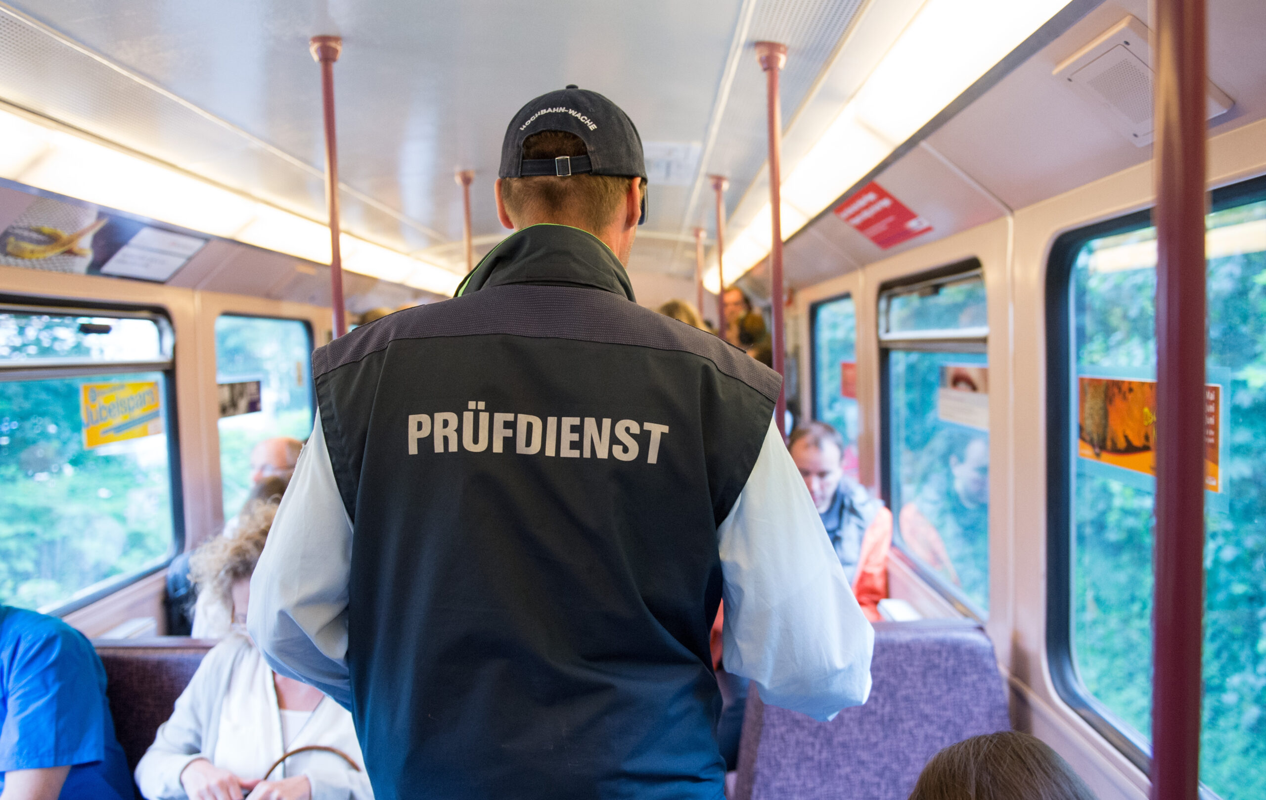 Ein Mitarbeiter der Hochbahn überprüft in einer U-Bahn die Fahrscheine von Reisenden.