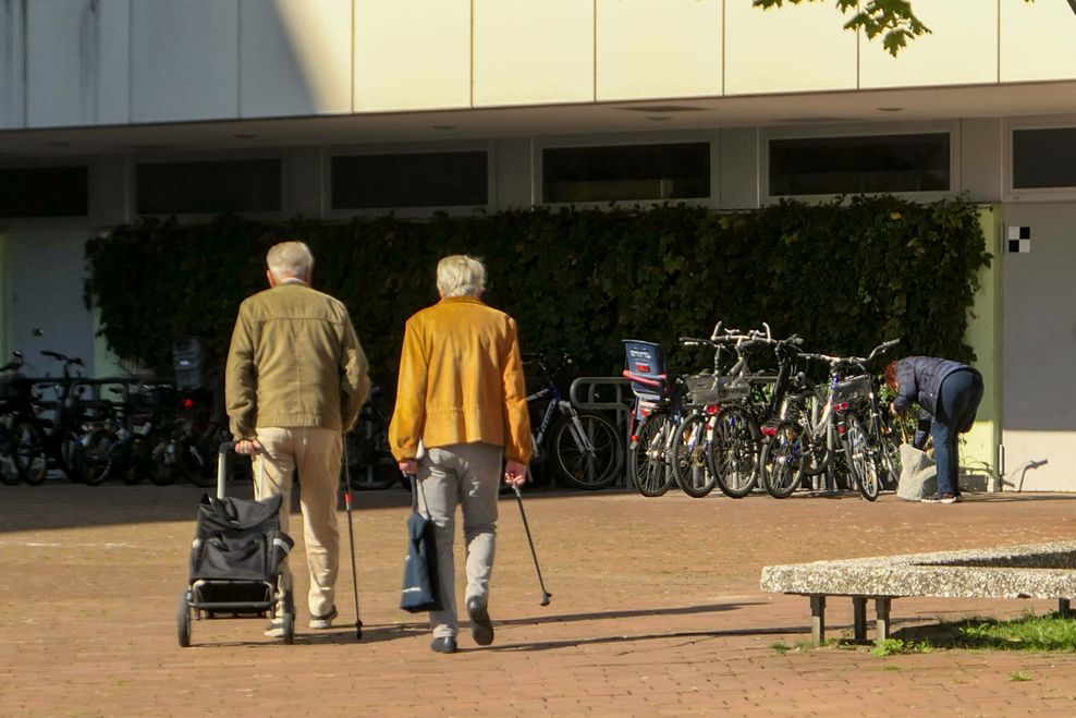 Ein Senior hat einen Trolley in der Hand.