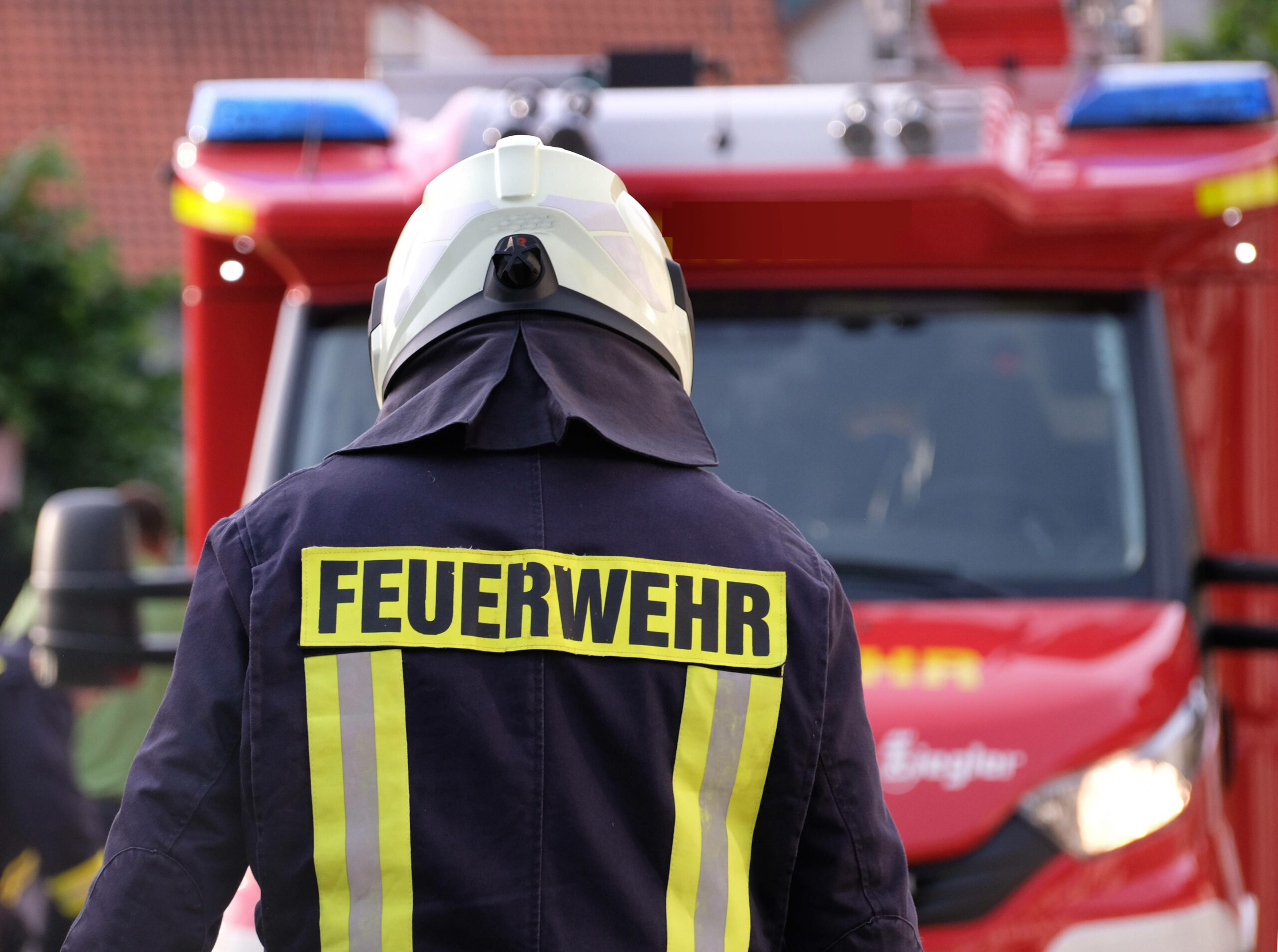 Eine Feuerwehrkraft steht vor einem Einsatzfahrzeug.