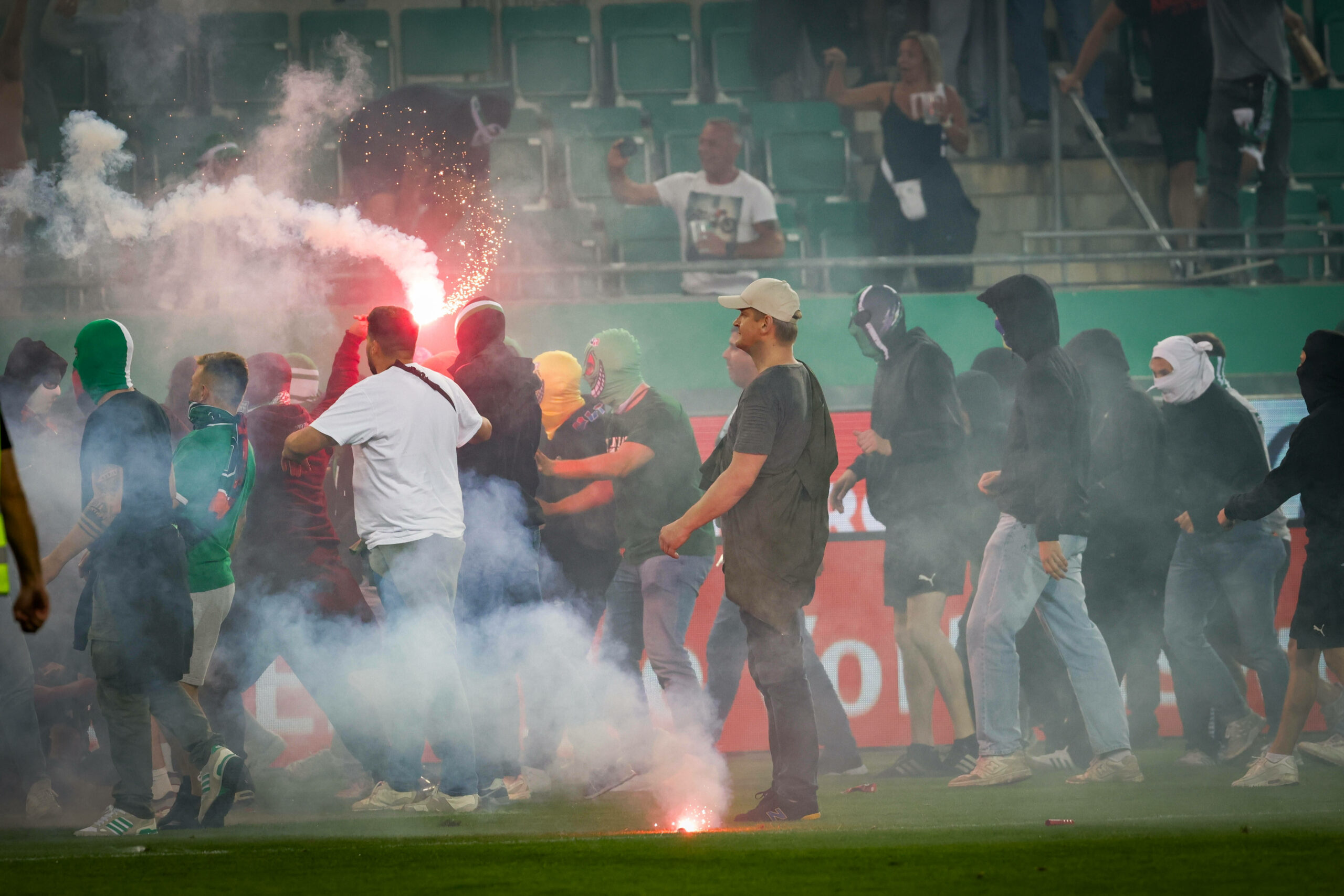 Pyrotechnik und maskierte Fans auf dem Spielfeld.