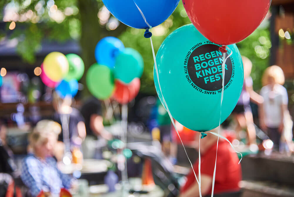 Bunte Luftballons mit der Aufschrift „Regenbogenkinderfest“