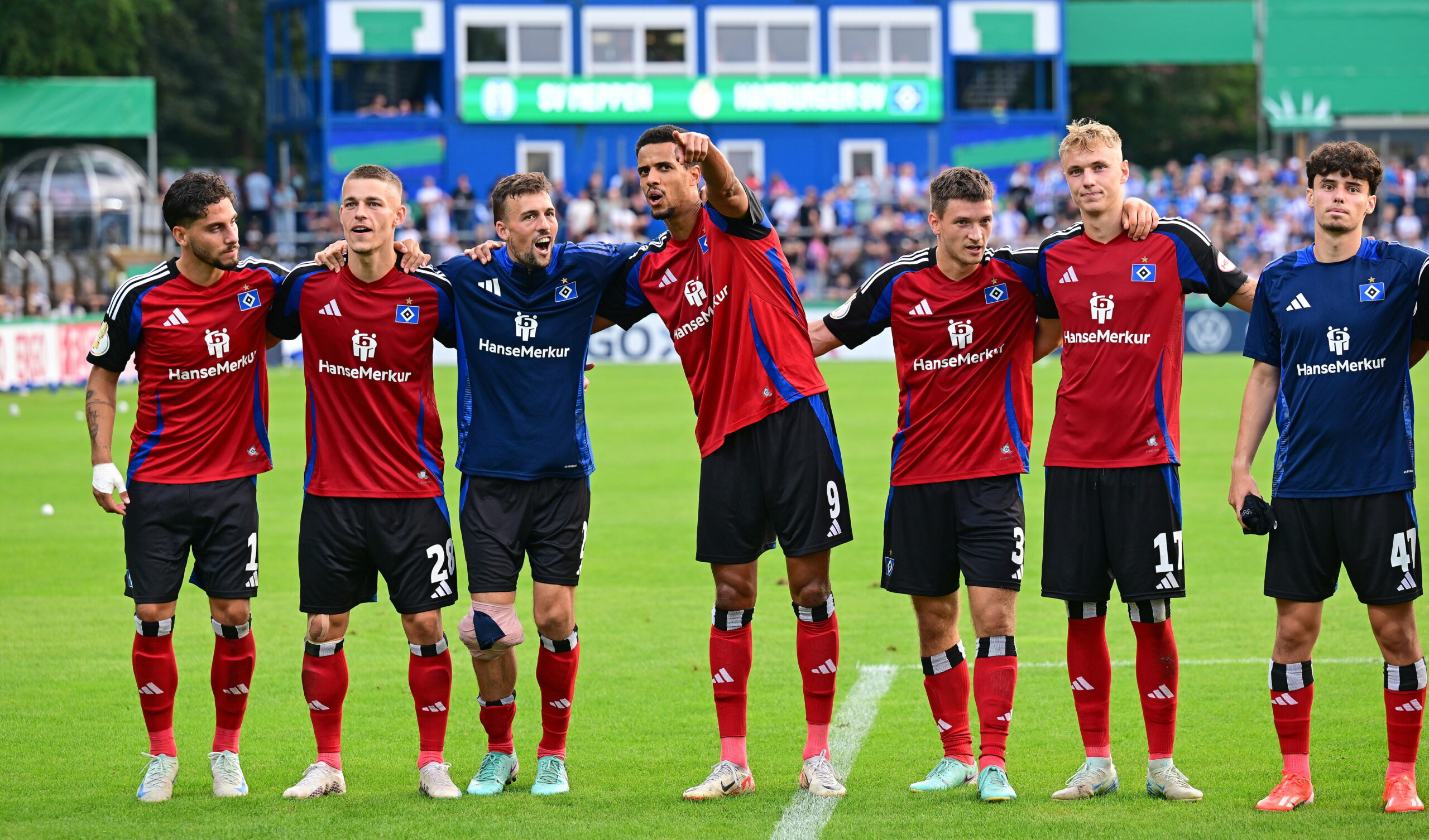 Ludovit Reis, Miro Muheim, Jonas Meffert, Robert Glatzel, Noah Katterbach, Adam Karabec und Nicolas Oliveira (v.l.) stehen Arm in Arm vor der HSV-Kurve