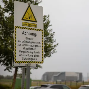 Ein Warnschild steht auf einem Parkplatz vor einem Flughafengelände
