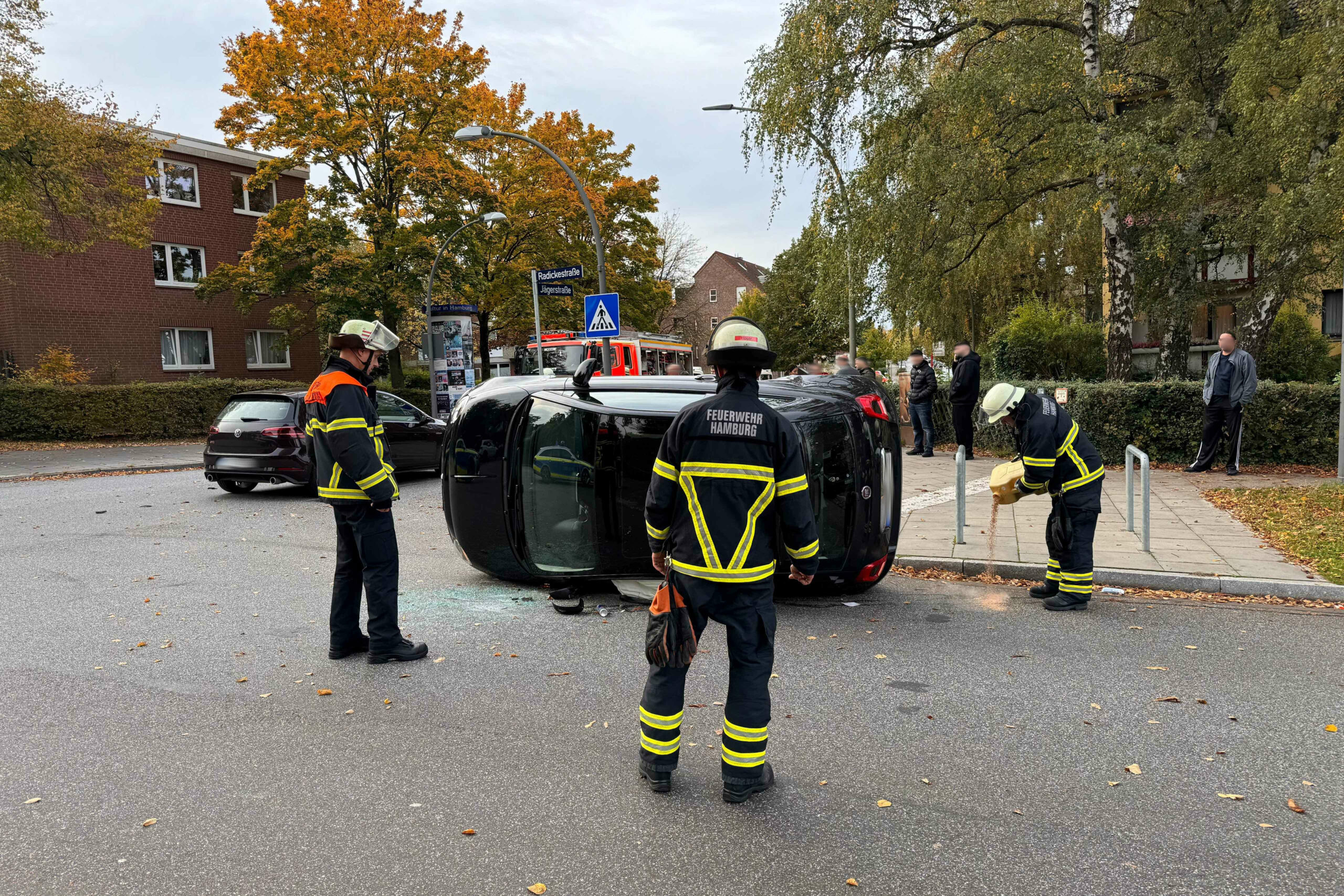 Feuerwehrkräfte stehen um den Fiat an der Unfallstelle.