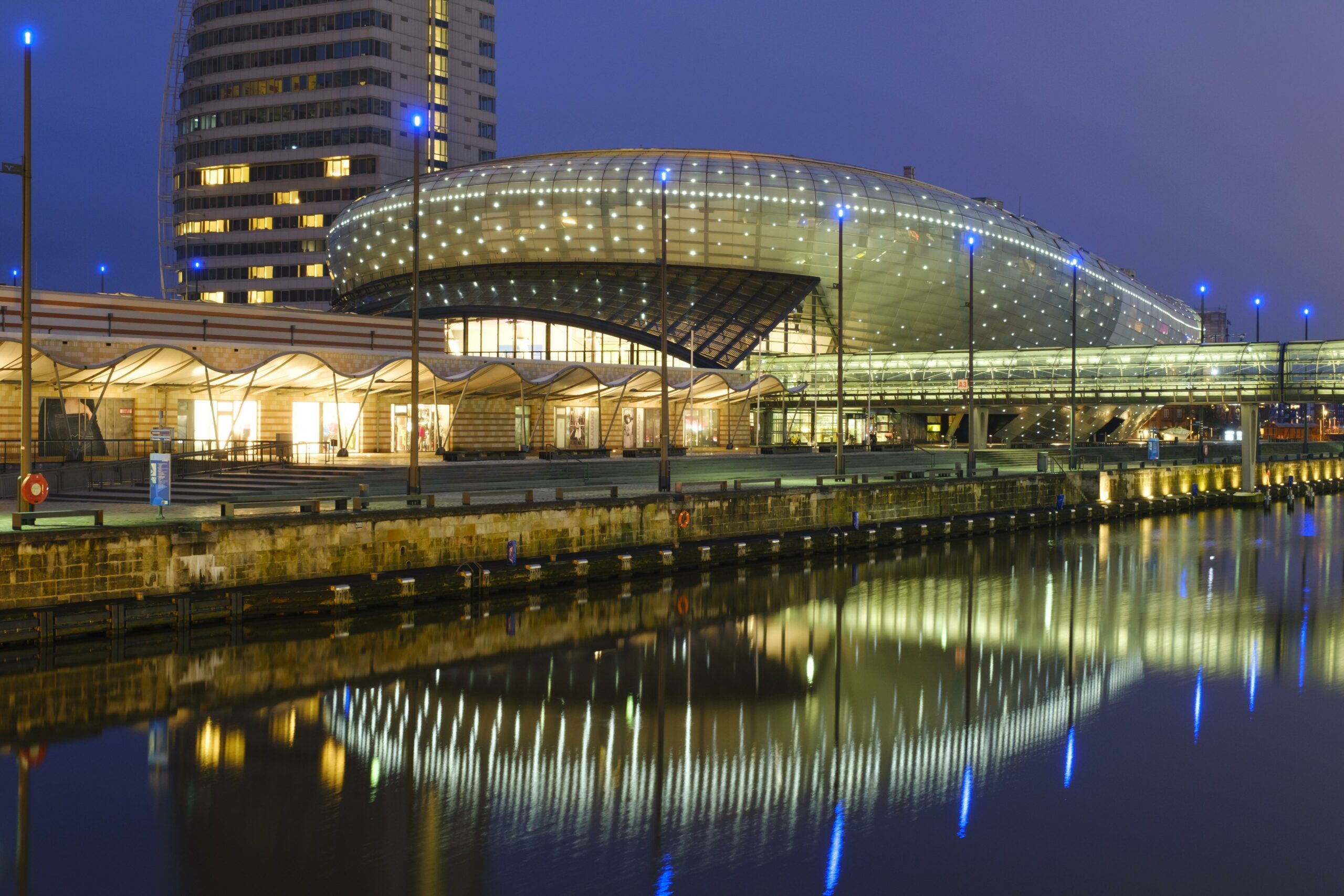 Ein futuristisches Gebäude am Wasser im Dunkeln