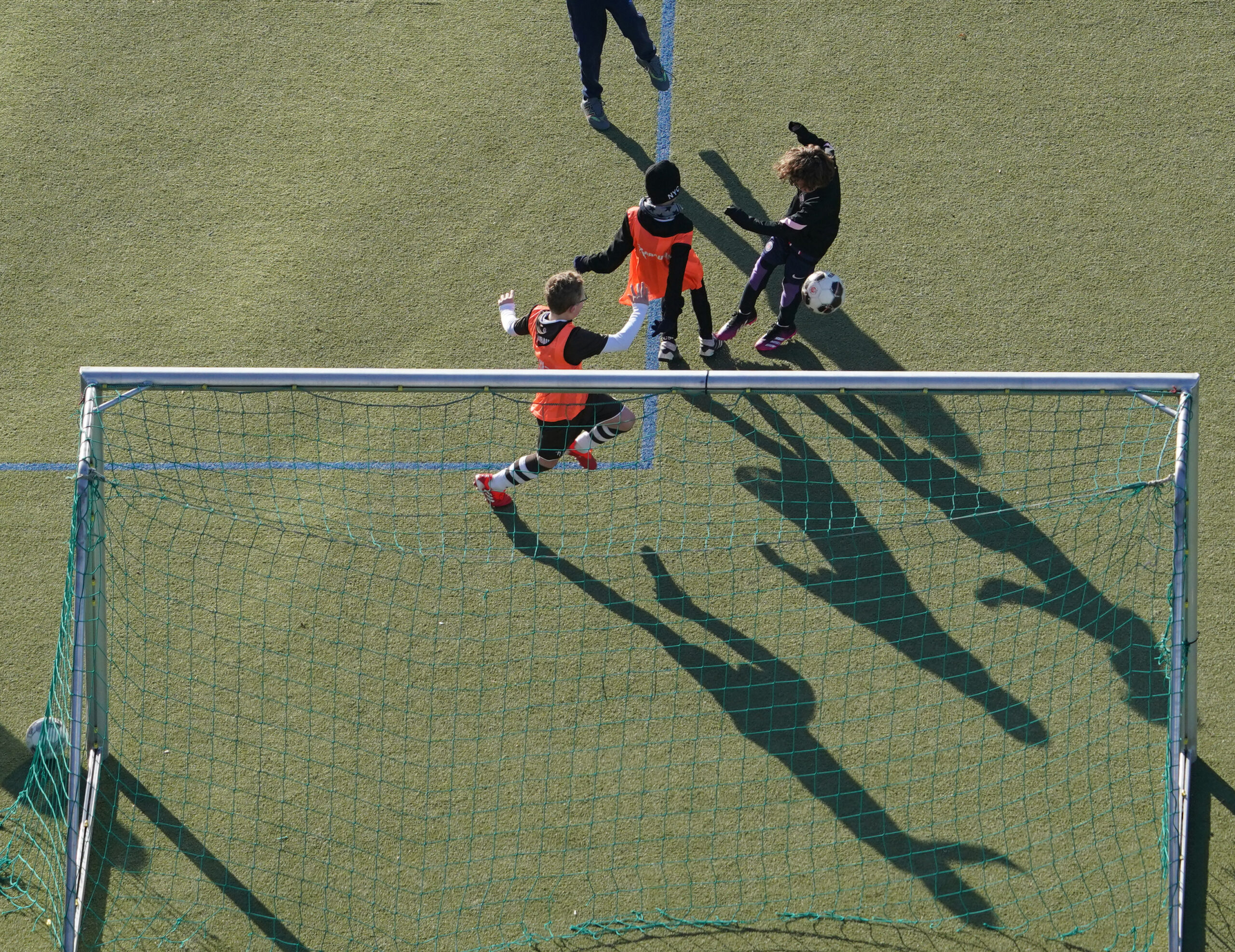 Kinder spielen auf einem Kunstrasenplatz Fußball.