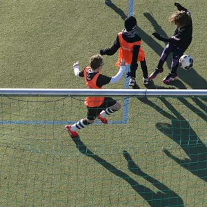 Kinder spielen auf einem Kunstrasenplatz Fußball.