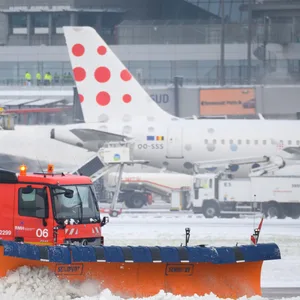 Eine Schneeräumungs-Fahrzeug schiebt den Schnee am Hamburger Flughafen weg. Im Hintergrund sieht man eine Maschine von „Eurowings“