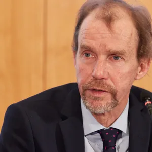 Mann mit Halbglatze spricht in ein Mikrofon