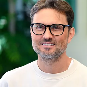 Regisseur Simon Verhoeven lächelt in hellem Sweatshirt in die Kamera