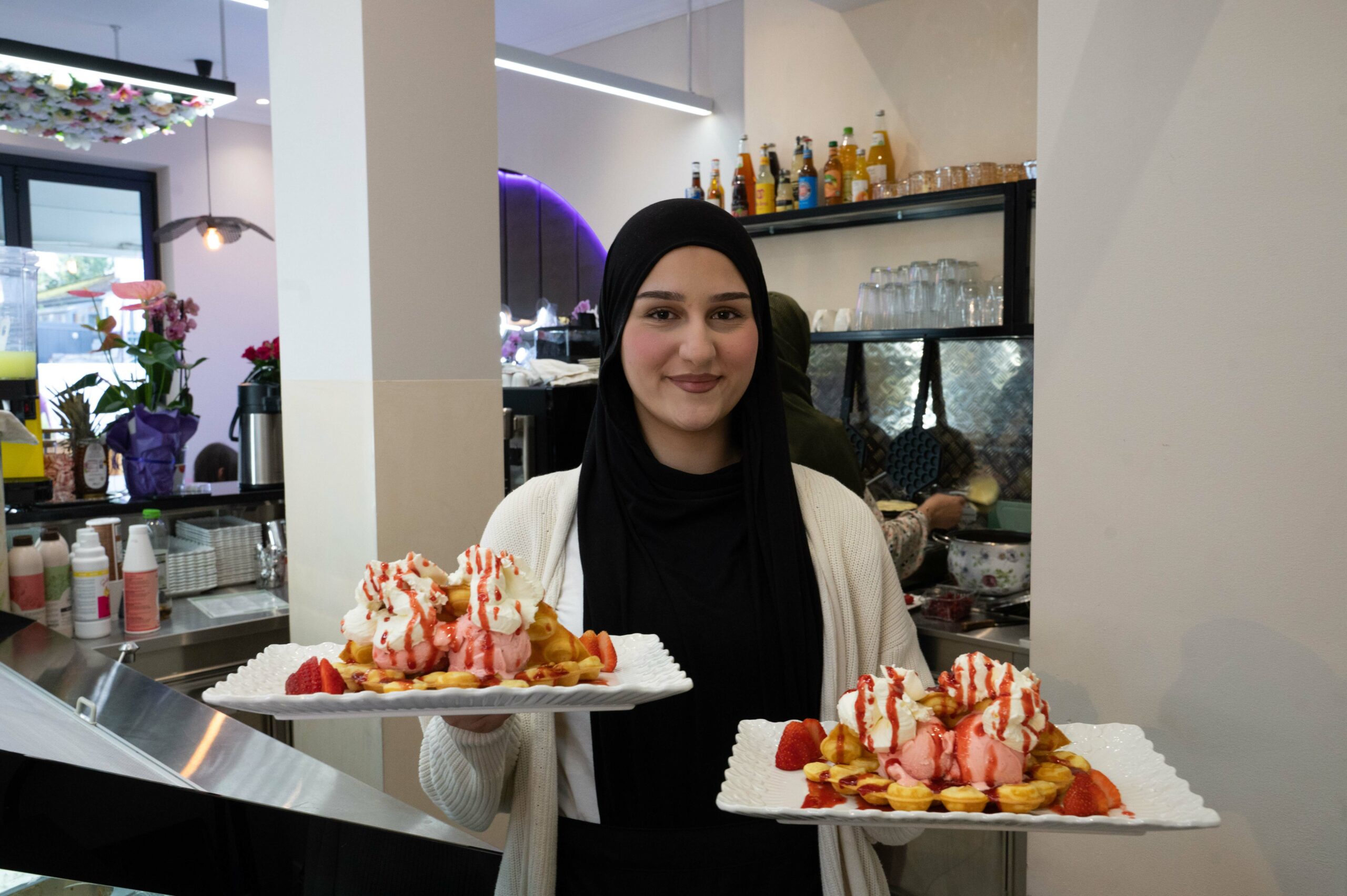 Sumeja Zumberi hält zwei Teller mit Waffeln in der Hand.