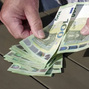 Eine ältere Männerhand zählt mehrere Hundert-Euro-Scheine