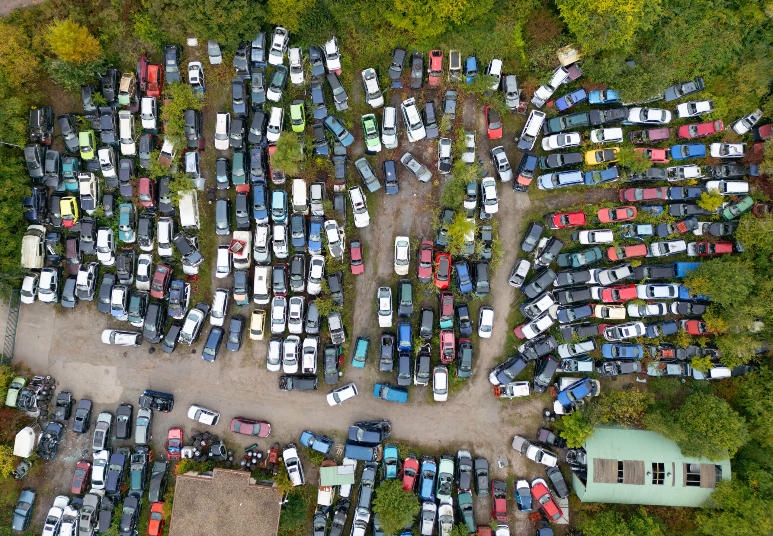 Ausgediente Verbrennerautos stehen auf einem Schrottplatz, dicht nebeneinander geparkt