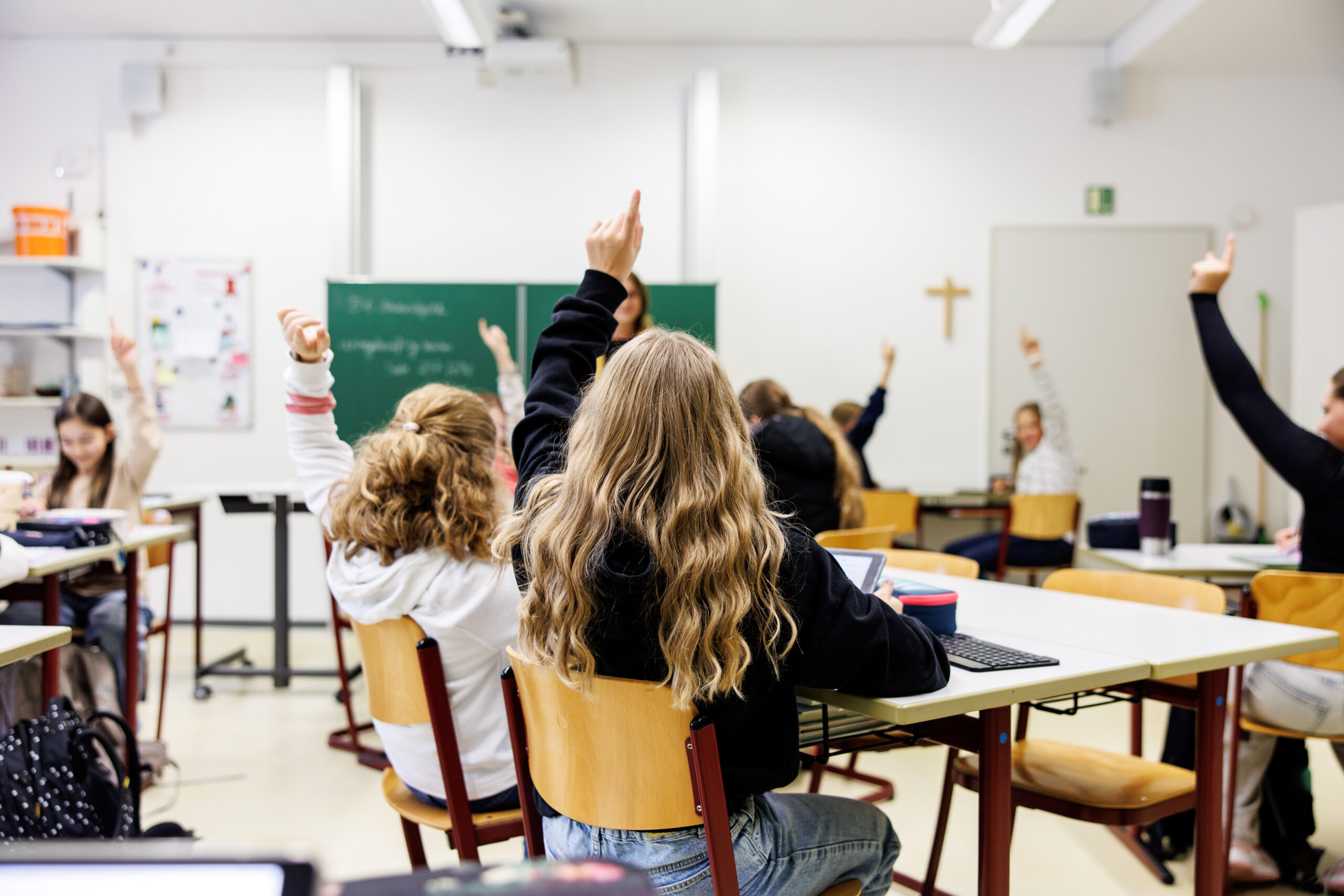 Schülerinnen einer sechsten Klasse melden sich in einem Klassenraum.