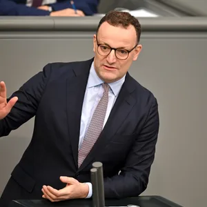 Jens Spahn steht im Anzug im deutschen Bundestag am Mikrofon und hält eine Rede