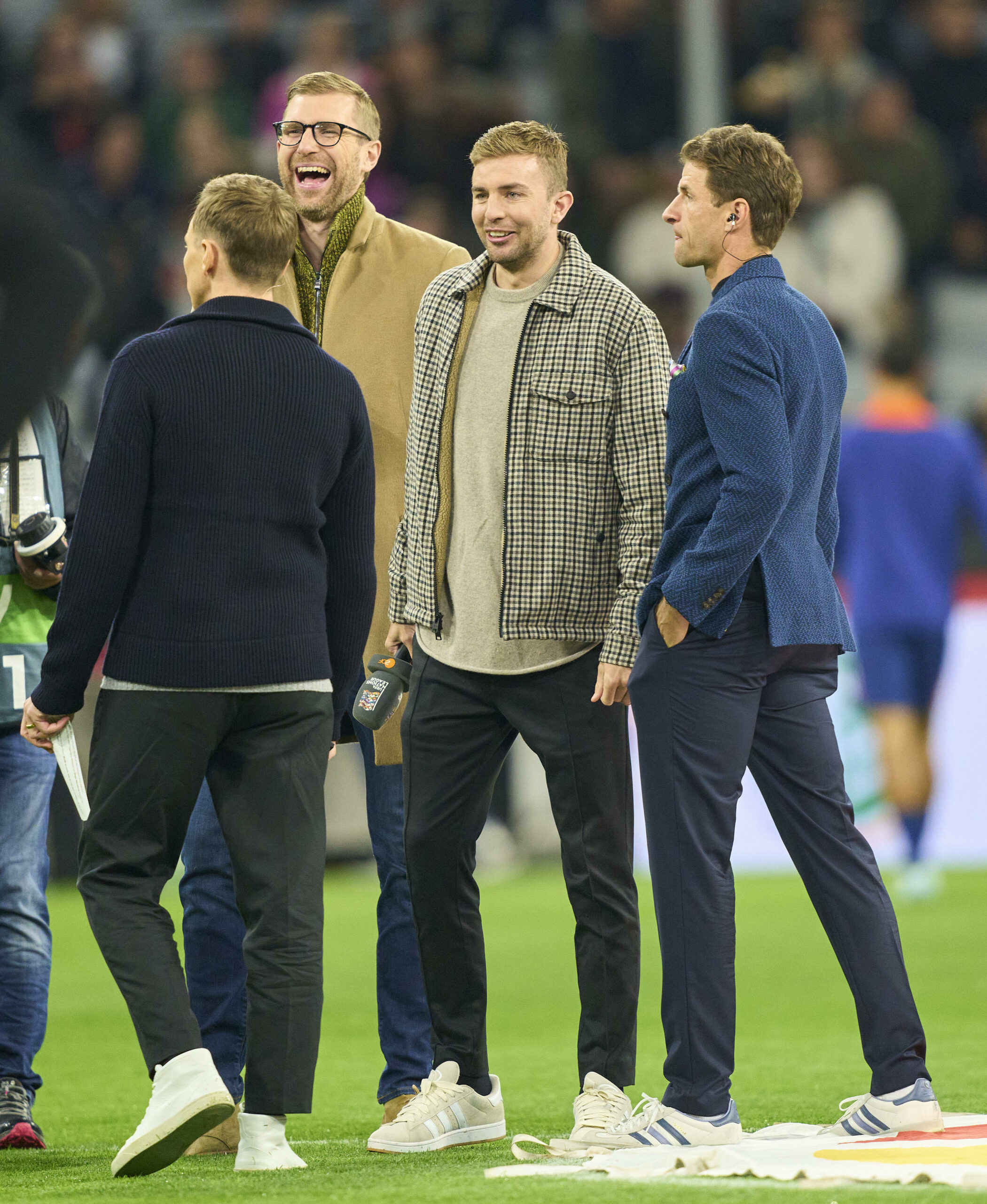 Per Mertesacker, Christoph Kramer und Thomas Müller lachen zusammen auf dem Rasen der Allianz-Arena