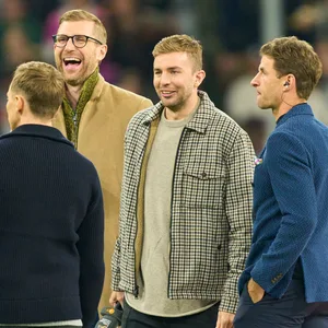 Per Mertesacker, Christoph Kramer und Thomas Müller lachen zusammen auf dem Rasen der Allianz-Arena