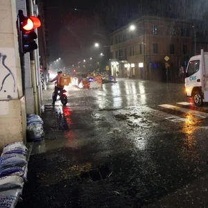 Ein Essenlieferant steht mit seinem Fahrrad in einer überschwemmten Straße