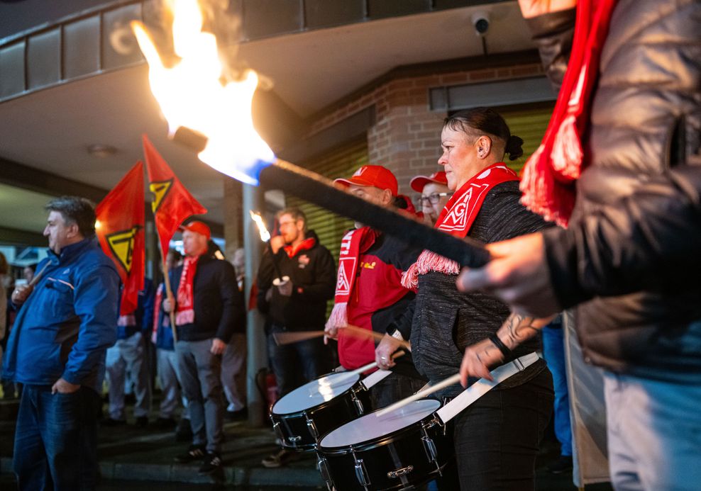 Mitarbeiter von Volkswagen stehen mit Fackeln vor dem VW Werk in Osnabrück.