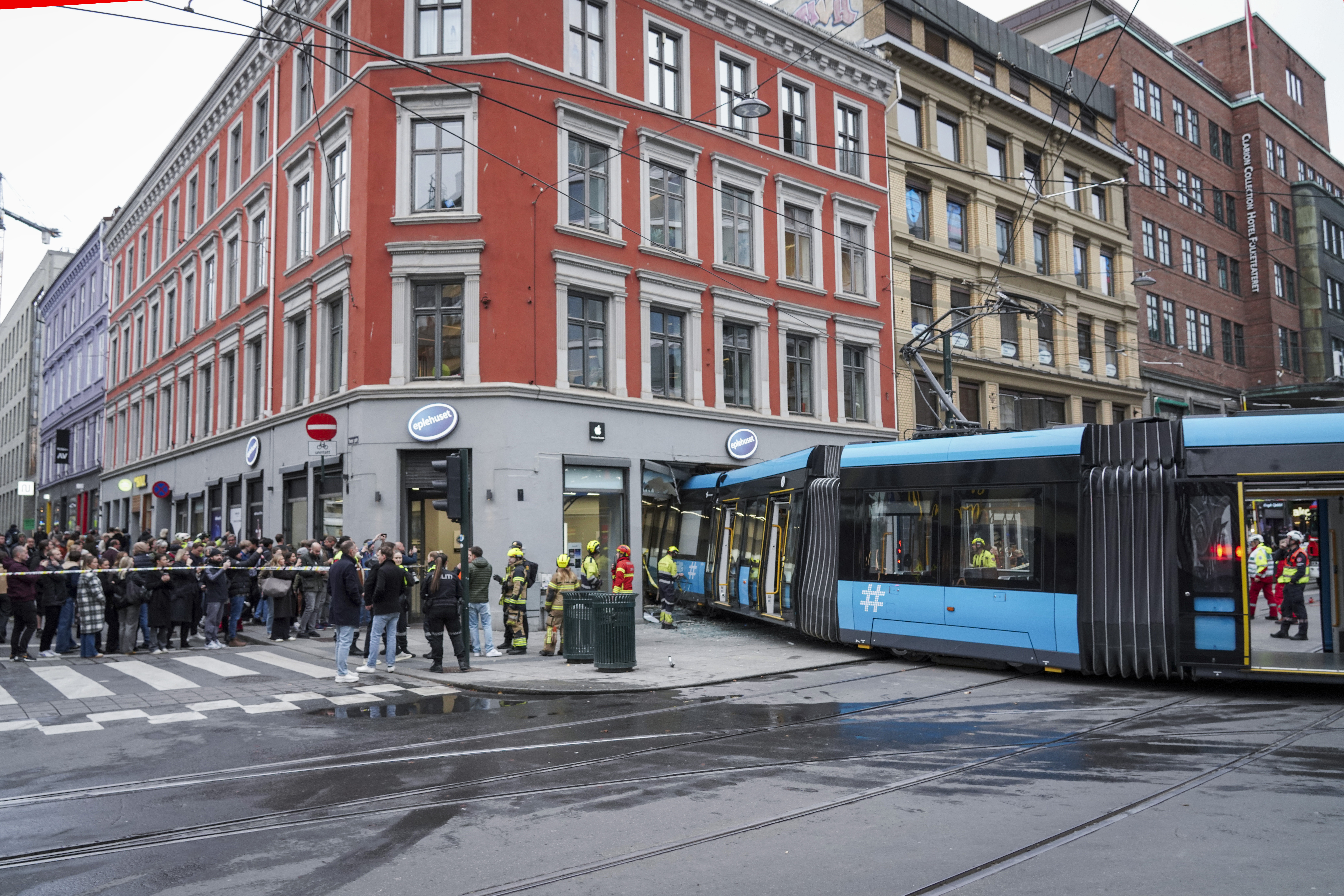 Menschen und Rettungskräfte versammeln sich an der Stelle, an der eine Straßenbahn entgleist und in ein Gebäude in der Innenstadt von Oslo (Norwegen) gefahren ist.