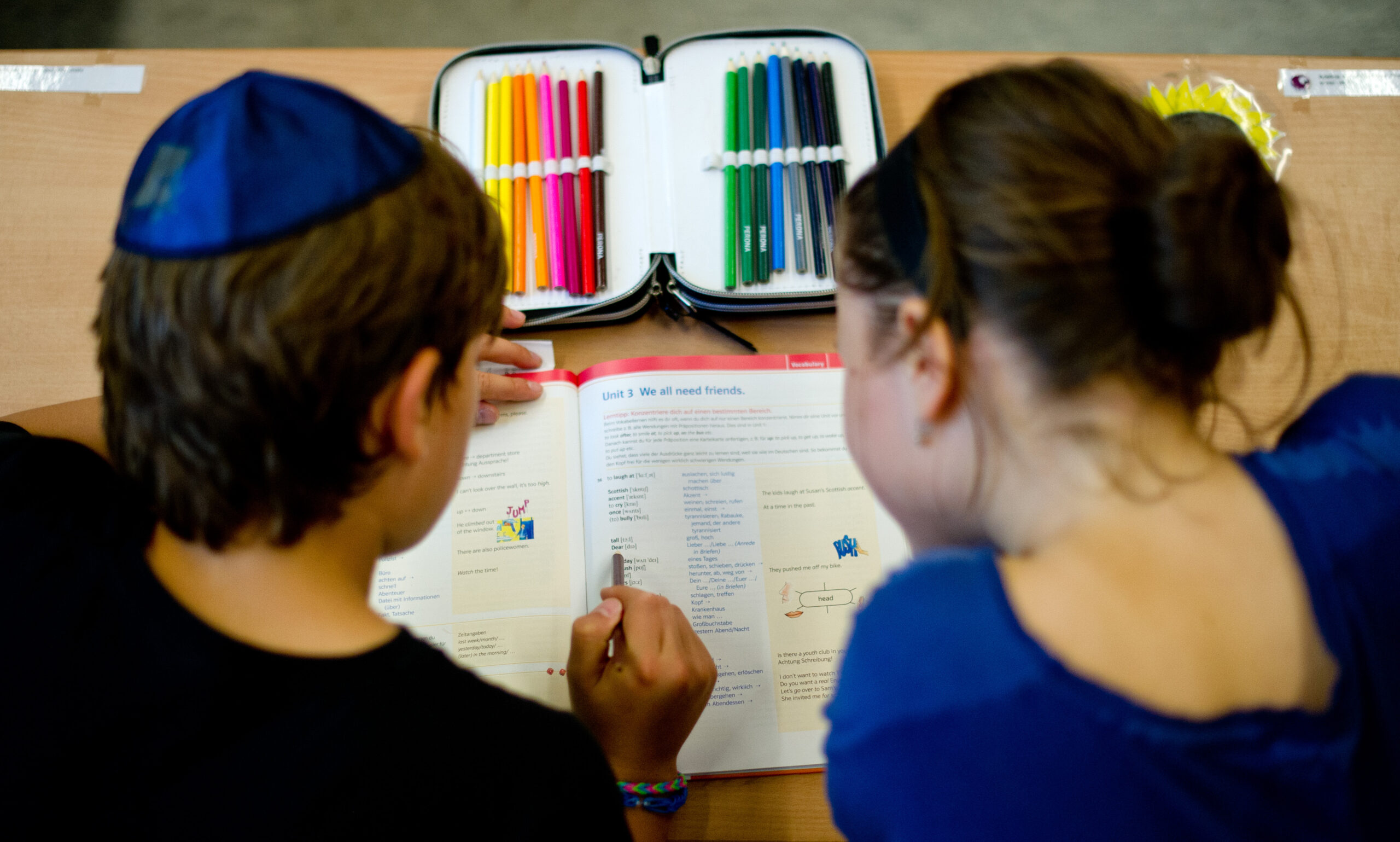 Schüler mit Kippa beugen sich über ein Schulheft