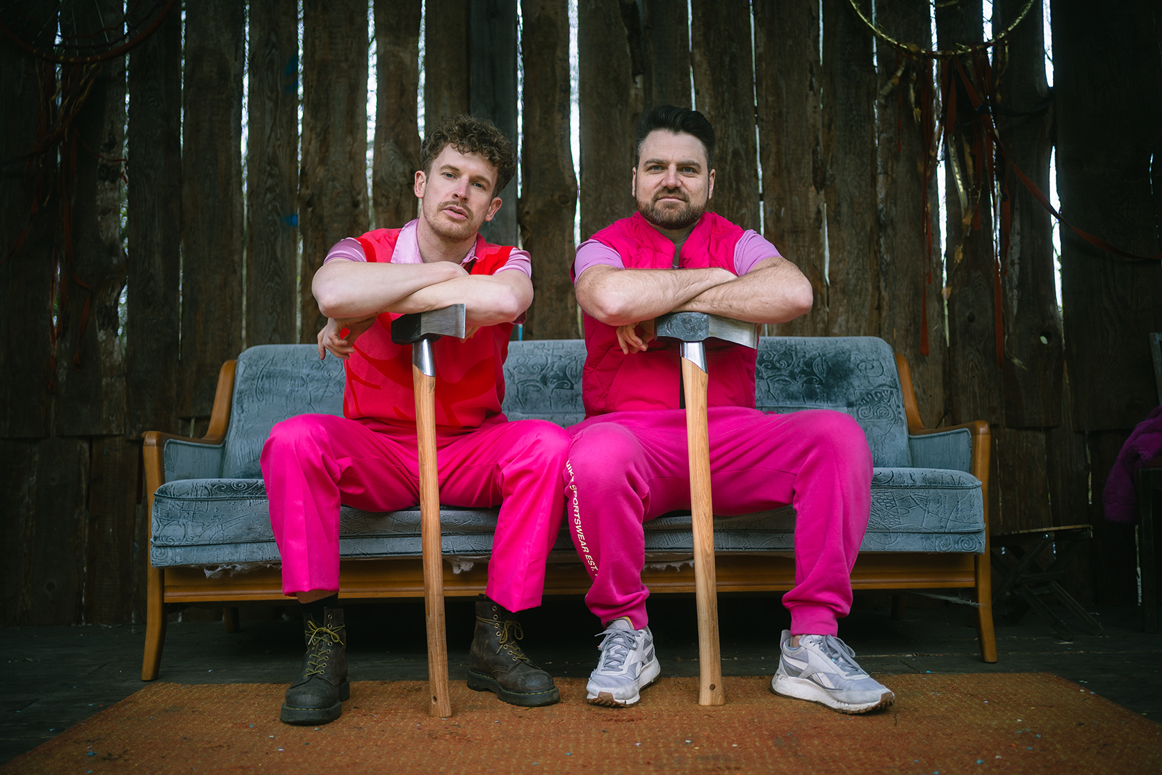 Lukas Klaschinski und Timo Neitzel sitzen in pinken Trainingsanzügen auf einem Sofa.