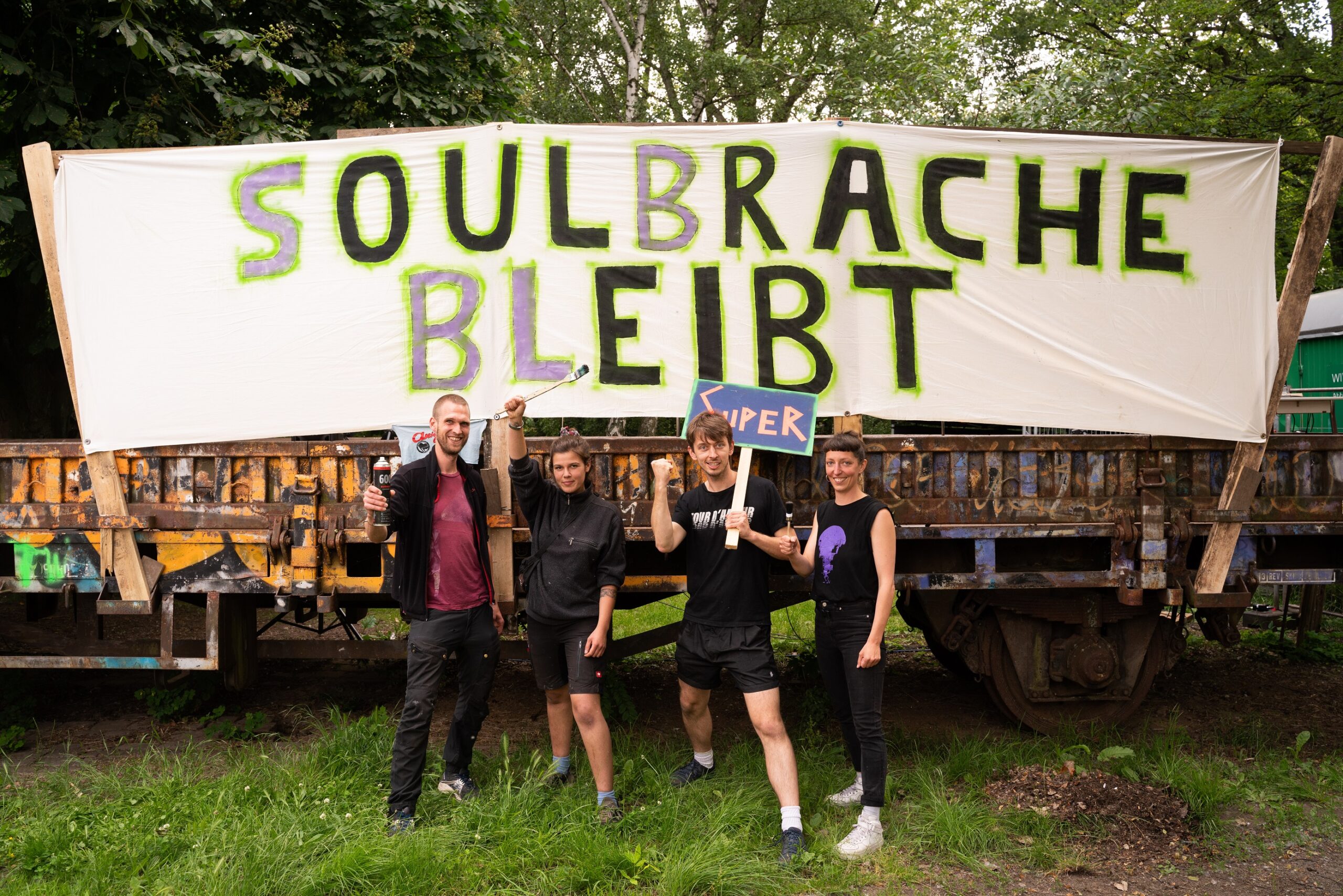 Menschen vor einem Plakat „Soulbrache bleibt“