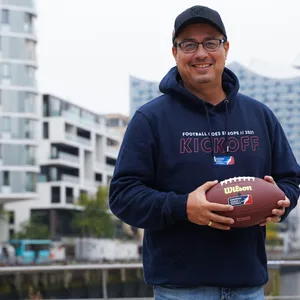 Shuan Fatah hält einen Football vor der Elbphilharmonie