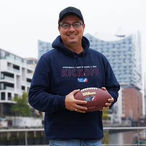 Shuan Fatah hält einen Football vor der Elbphilharmonie