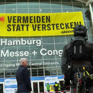 Greenpeace-Aktivisten haben ein riesiges Banner über dem Eingang zu den Messehallen angebracht.