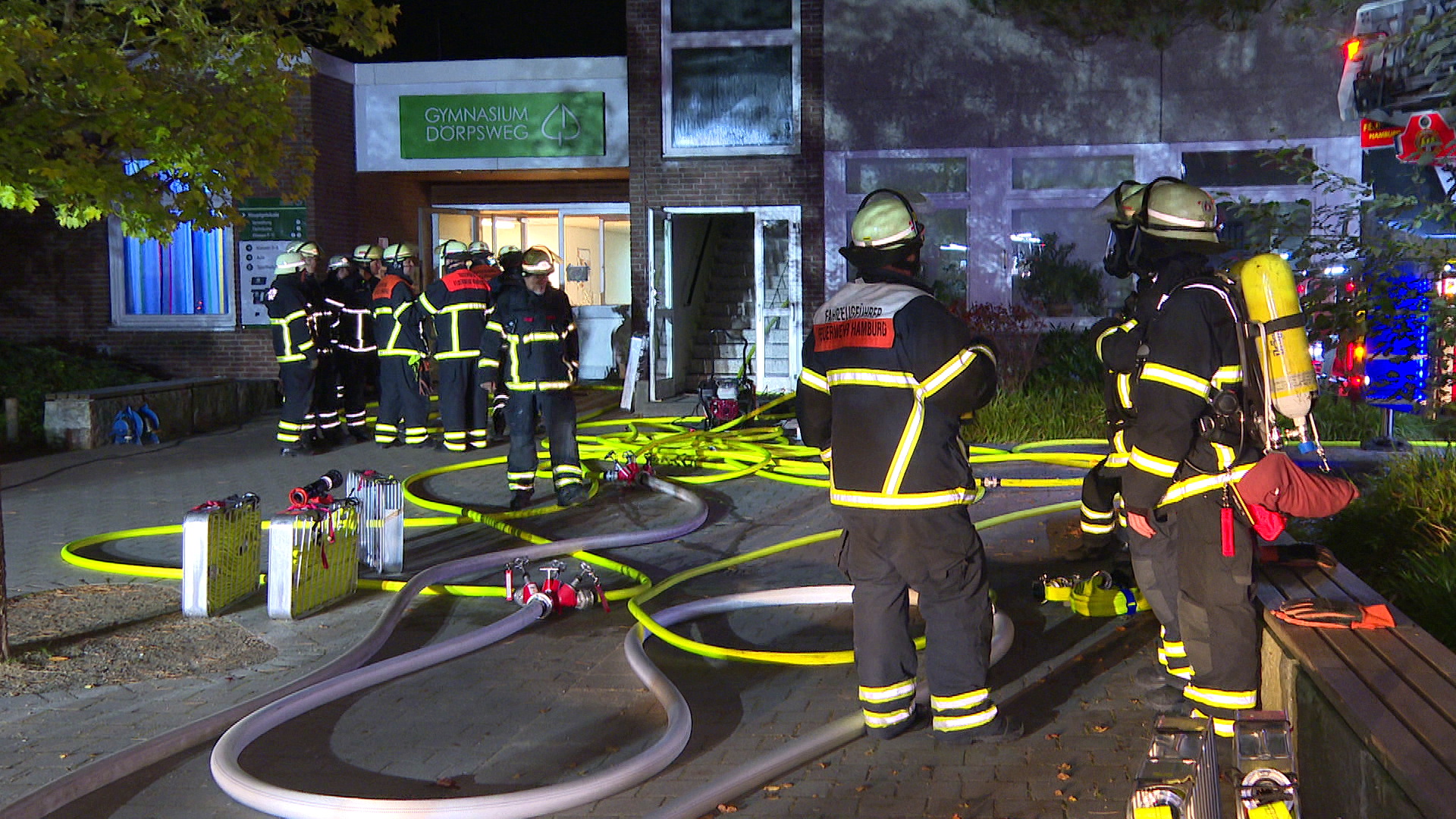 Feuerwehrleute stehen vor dem Schulgebäude