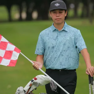 Jeffrey Guan steht in Polohemd auf einem Golfplatz, mit Fahne und Schlägern in der Hand