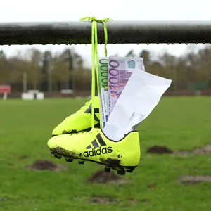 Briefumschlag mit Geldscheinen steckt in Fußballschuhen