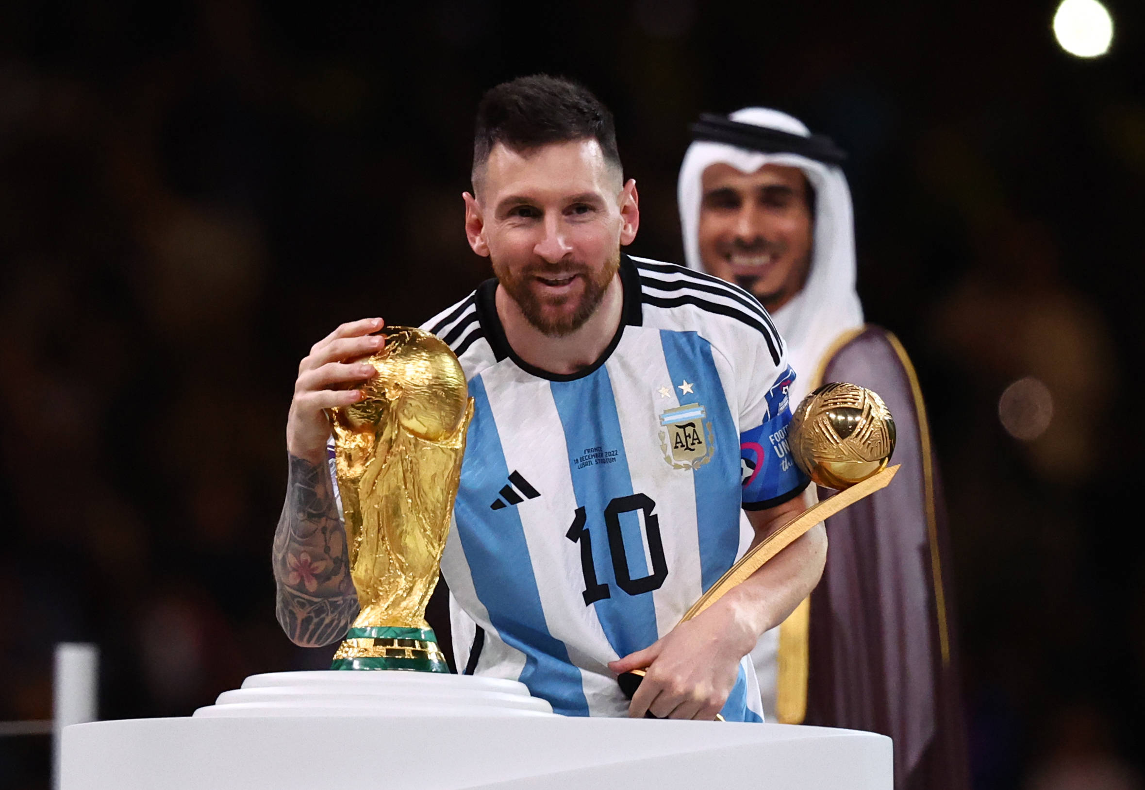 Lionel Messi im argentinischen Nationaltrikot streichelt den WM-Pokal