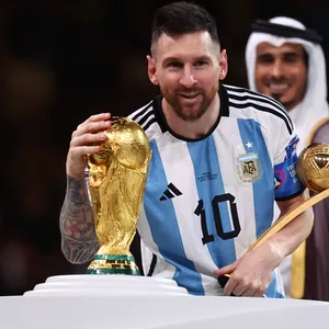 Lionel Messi im argentinischen Nationaltrikot streichelt den WM-Pokal